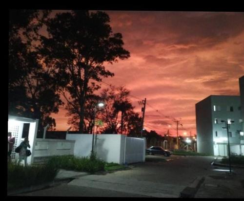 a sunset in a parking lot with a building at POUSADA PERLLA's Pindamonhangaba in Pindamonhangaba