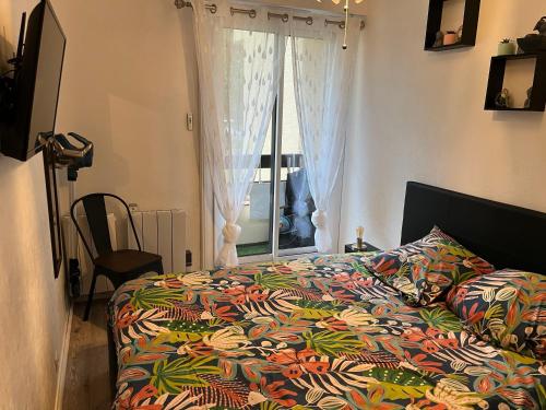 - un lit avec une couette colorée et une fenêtre dans l'établissement Appartement cosy proche plage, à Cabourg