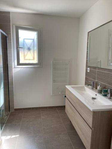 une salle de bain avec un lavabo, un miroir et une fenêtre dans l'établissement VILLA avec piscine clim jolie vue Camargue, à Saint-Gilles