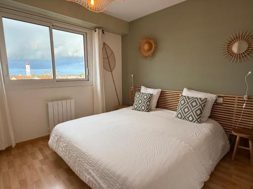 a bedroom with a white bed with a window at Vue sur l'entrée du port in Saint-Gilles-Croix-de-Vie
