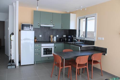 une cuisine avec des armoires vertes, une table et des chaises dans l'établissement La petite maison dans la pâture, à Vaudricourt