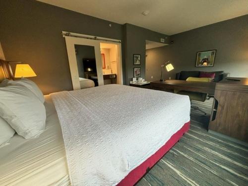 a hotel room with a large bed and a living room at Hampton Inn & Suites Deptford, Nj in Deptford
