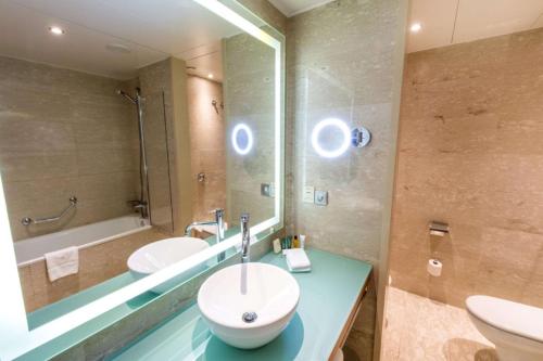 a bathroom with a sink and a mirror and a tub at Hilton Diagonal Mar Barcelona in Barcelona
