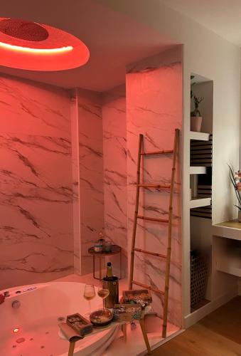 La salle de bains est pourvue de murs en marbre rose et d'une échelle. dans l'établissement Suite-Luxe-Love-Detente, à Troyes