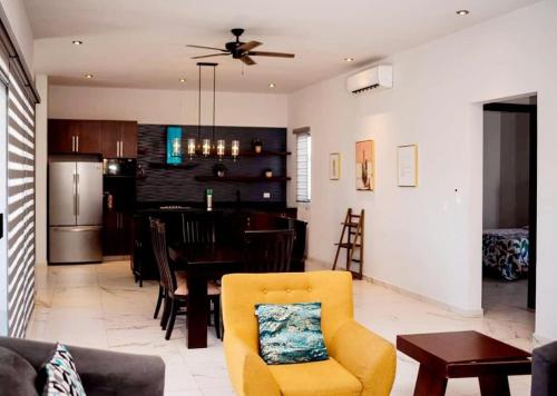 a living room with a yellow chair and a kitchen at Casa Residencia de Renta en Country Club, San Carlos Sonora in El Caballito