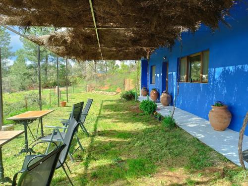 a blue house with chairs and tables in a yard at Apartamento Rural La Frondosa in Villasbuenas de Gata