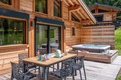 une terrasse avec une table et des chaises ainsi qu'un bain à remous dans l'établissement Chalet Seven Summits - Pool - Sauna - Jacuzzi - By Cozee Rentals, à Chamonix-Mont-Blanc