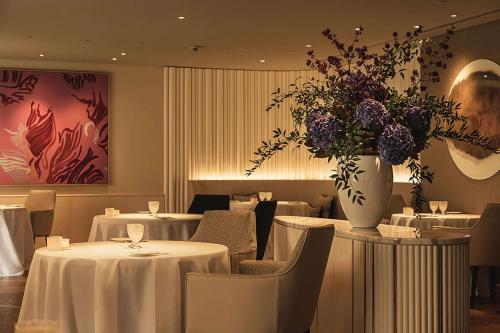 a restaurant with tables and chairs and a vase of flowers at Waldorf Astoria Amsterdam in Amsterdam