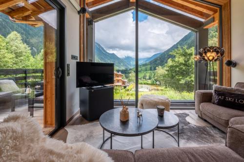 un salon avec une table et une grande fenêtre dans l'établissement Chalet Seven Summits - Pool - Sauna - Jacuzzi - By Cozee Rentals, à Chamonix-Mont-Blanc