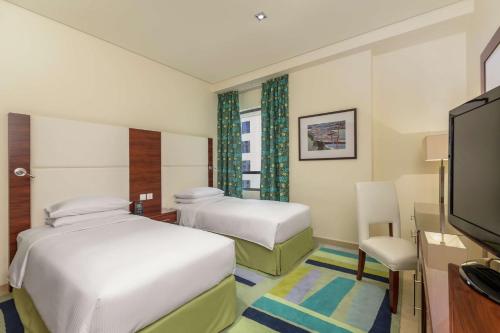 a hotel room with two beds and a flat screen tv at Hilton Dubai The Walk in Dubai