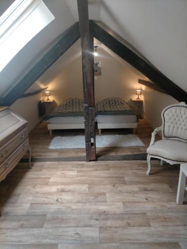 Cette chambre mansardée comprend deux lits et une chaise. dans l'établissement S Bourgeois 2 Charmant T3 tout équipé au centre, à Sedan