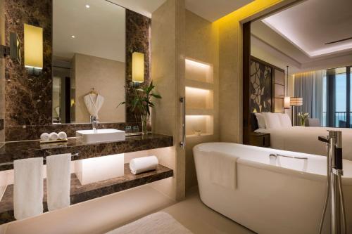 a bathroom with a tub and a large mirror at Hilton Wenchang in Wenchang