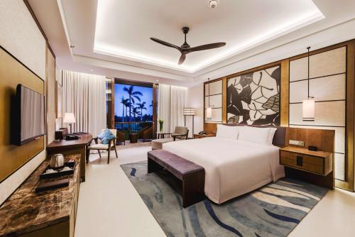a bedroom with a large white bed and a desk at Hilton Wenchang in Wenchang