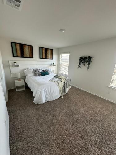 a white bedroom with a bed and two windows at Spacious 4-Bedroom Retreat with High-Speed WiFi and Tranquil Ambiance in Aubrey