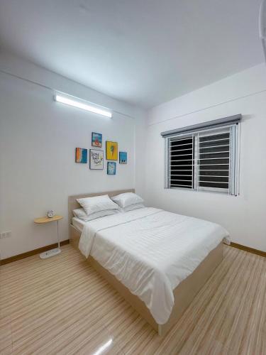 a white bedroom with a large bed and a window at Nhà Shi Homestay in Hue