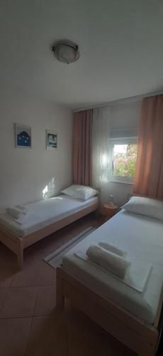a bedroom with two beds and a window at Apartmani Presečki in Pag