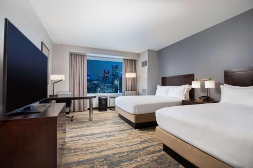 a hotel room with two beds and a flat screen tv at Hilton Americas - Houston in Houston