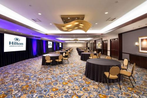 a banquet hall with tables and chairs and a sign at Hilton Americas - Houston in Houston