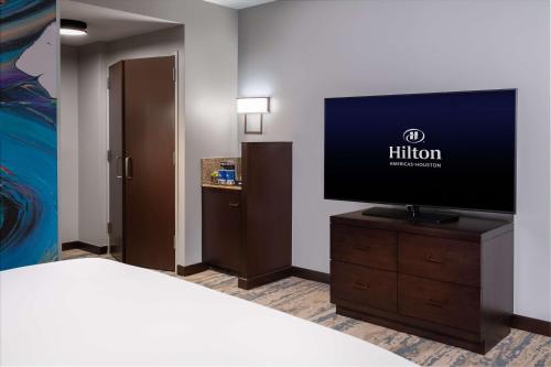 a hotel room with a bed and a flat screen tv at Hilton Americas - Houston in Houston