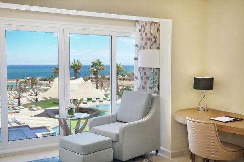 a hotel room with a desk and a chair and a view of the ocean at Hilton Hurghada Plaza Hotel in Hurghada