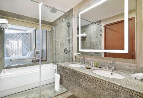 a bathroom with two sinks and a tub and a mirror at Hilton Hurghada Plaza Hotel in Hurghada