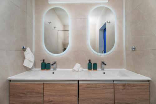 Modern seaview apartment in the heart of Agia Napa في أيا نابا: حمام مع مغسلة بيضاء ومرآتين