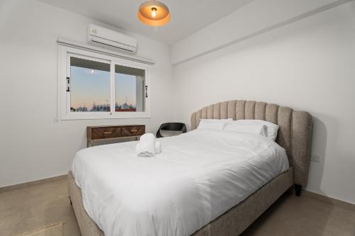 Modern seaview apartment in the heart of Agia Napa في أيا نابا: غرفة نوم بسرير كبير ونافذة