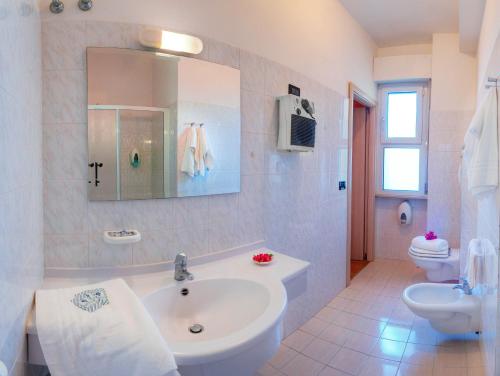 een badkamer met een wastafel, een toilet en een spiegel bij Hotel Mondial in Porto Recanati