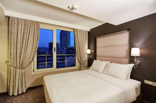 a bedroom with a large bed and a large window at DoubleTree by Hilton Izmir - Alsancak in Izmir