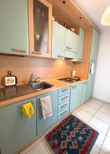 - une cuisine avec des placards bleus, un évier et un tapis dans l'établissement Charme Appartement avec Terrasse, à Cannes