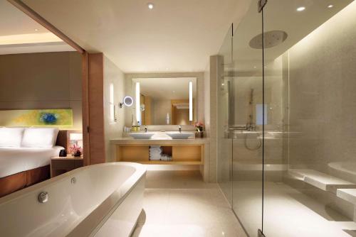 a bathroom with a tub and a bed and a sink at DoubleTree by Hilton Johor Bahru in Johor Bahru