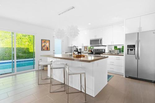 una cocina con armarios blancos y una isla con taburetes. en Paseo Passing Luxe Palm Desert Pool Home Firepit, en Palm Desert