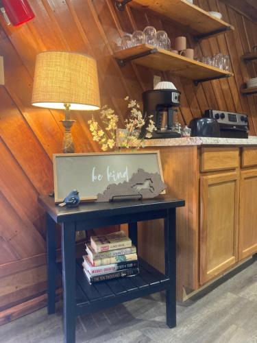 a table in a kitchen with a lamp and books at Restful River Cabin, Red River Gorge, KY, River Access & Views in Stanton