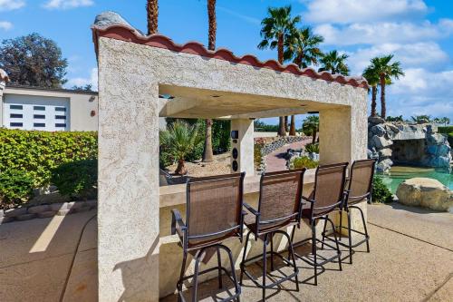 a group of chairs on a patio with a pool at Cool Pool Retreat in Bermuda Dunes