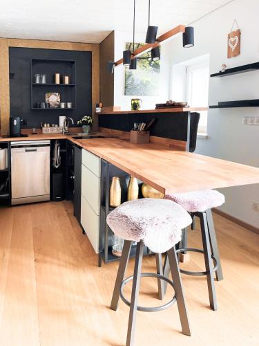 a kitchen with a wooden counter and two stools at Exklusives Design Hideaway & Sauna in Warngau