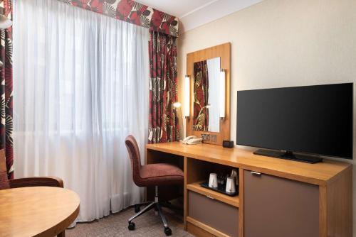 a hotel room with a desk with a flat screen tv at Hilton London Olympia in London