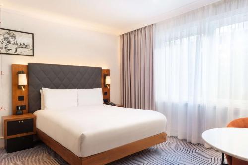 a hotel room with a bed and a window at Hilton London Olympia in London