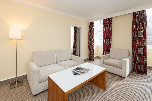 a living room with two chairs and a coffee table at Hilton London Olympia in London