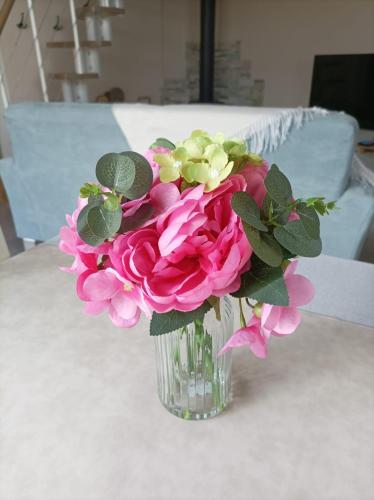 a vase filled with pink flowers on a table at " L'instant Nid d'où " , Spa et Luxe Intime in Baneuil
