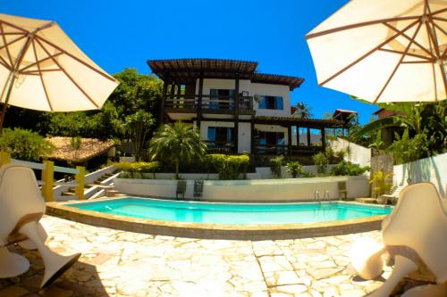 a house with a swimming pool and two umbrellas at Solange apartment-Casa em Ilheus-Olivença in Olivença