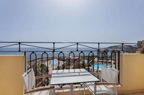 a table and chairs on a balcony with a view at Hilton Malta in St Julian's