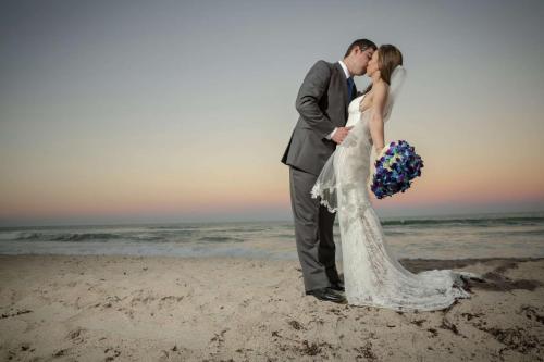 a bride and groom kissing on the beach at Hilton Melbourne Beach Oceanfront in Melbourne