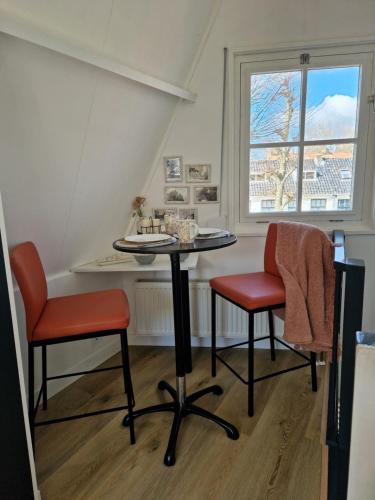 a table and two chairs in a room with a window at Bed & Breakfast De Punt in Monnickendam
