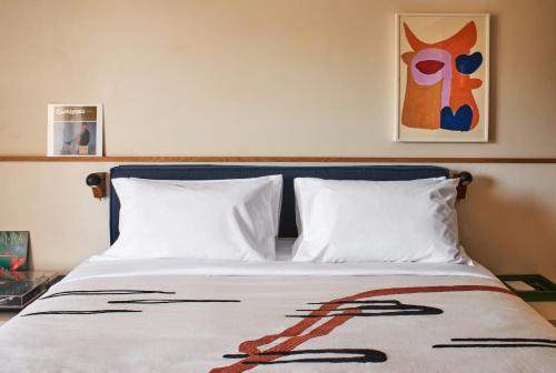 a bed with two white pillows and a painting on the wall at Ace Hotel & Swim Club Athens in Athens