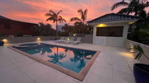 ein Pool vor einem Haus mit Sonnenuntergang in der Unterkunft Villa Kaminda - 8 persoons Villa in Vista Royal, Jan Thiel in Jan Thiel