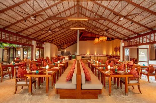 a dining room with wooden tables and chairs at Conrad Maldives Rangali Island in Mandhoo