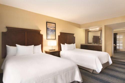 a hotel room with two beds with white sheets at Embassy Suites by Hilton Bloomington/Minneapolis in Bloomington