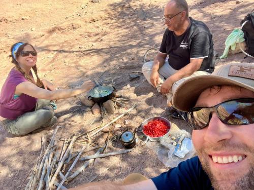 a group of three people sitting around a campfire at Dana Valley Tourism Hotel in Dana