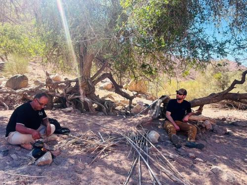 two men sitting on the ground under a tree at Dana Valley Tourism Hotel in Dana