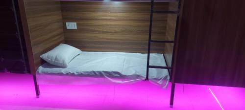 a bunk bed in a room with a pink light at Sharda Residency and Dormitory in Bikaner